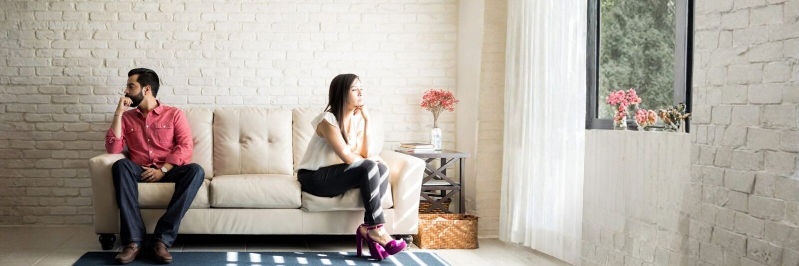 Image of a couple, each sitting at a different end of a sofa with their backs to each other - illustrating the home page of Evans Solicitors, a family law practice offering divorce and separation advice to clients in Milton Keynes and Buckinghamshire.